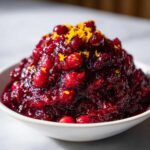 A close-up of rich, homemade cranberry sauce topped with bright orange zest.