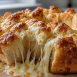 Close-up of freshly baked cheese bread with extreme cheese pull, featuring golden crust and gooey melted cheese.