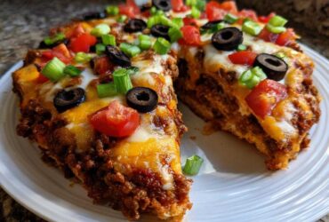 A thick slice of amazing mexican pizza topped with melted cheese, ground beef, black olives, tomatoes, and green onions.