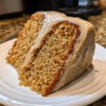 Close-up of a moist slice of spice cake layered with rich, creamy frosting.