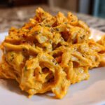 Close-up of penne pasta coated in rich, orange butternut squash pasta sauce and sprinkled with herbs.