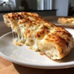 A close-up of a thick slice of white pizza with incredibly gooey, stretching mozzarella cheese.