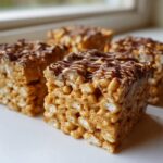 Four thick, chewy peanut butter rice krispie treats topped with a drizzle of melted chocolate.