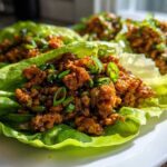 Close-up of savory chicken lettuce wraps filled with ground chicken mixture and topped with green onions.