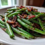 Close-up of vibrant green beans tossed with crispy bacon pieces, ready to serve.