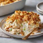 A scoop of creamy hot chicken salad topped with crunchy cornflakes served on a white plate.