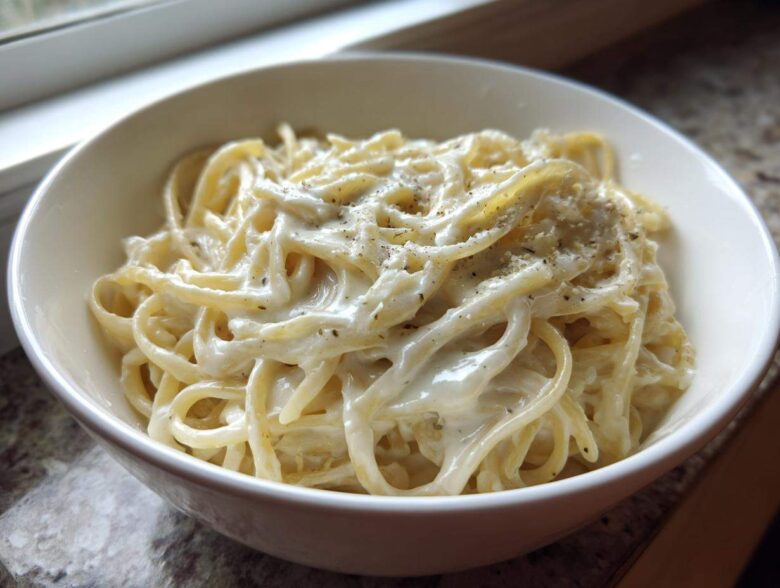 Close-up of fettuccine pasta generously coated in creamy homemade olive garden alfredo sauce and topped with pepper.