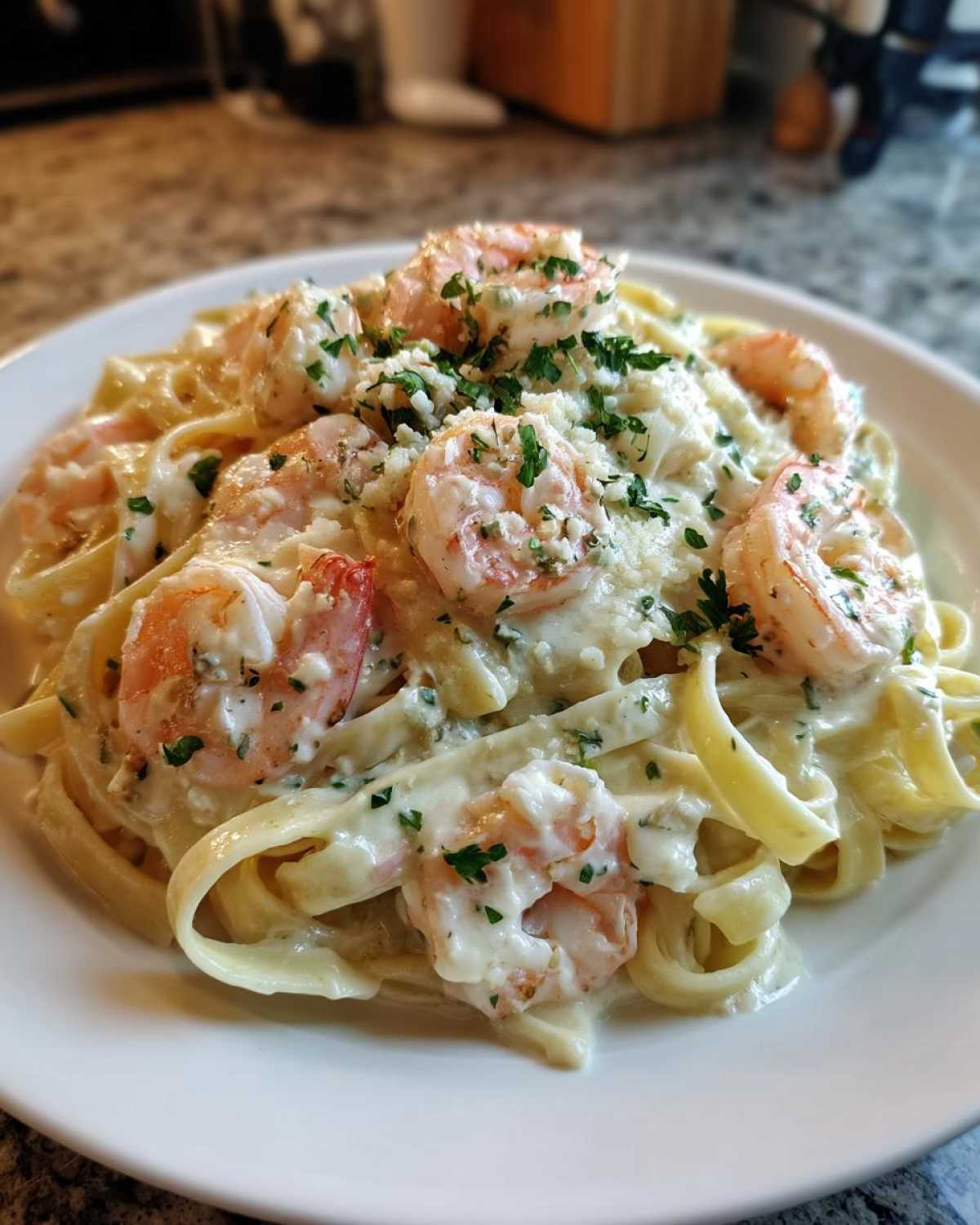 Close-up of rich shrimp alfredo pasta tossed in creamy sauce and garnished with parsley.