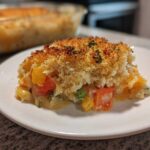 A serving of creamy vegetable casserole with mixed vegetables and a golden, crispy breadcrumb topping.