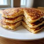 A stack of four fluffy banana pancakes, cut open to show the soft interior texture.