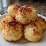 A pile of golden brown, pan-fried potato dumplings served on a white plate.