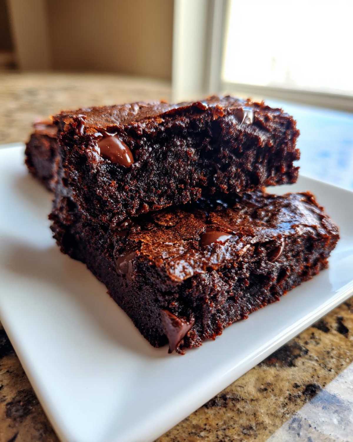 Two stacked, fudgy slices of dark chocolate black bean brownies with visible melted chocolate chips.