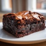 A close-up of a rich, fudgy square of Oreo brownies showing a visible Oreo cookie layer inside.