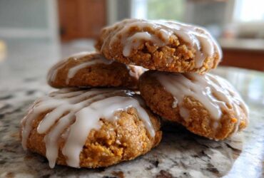 A stack of four soft, spiced persimmon cookies topped with a thick white glaze.