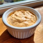 Close-up of creamy, orange-tinted big mac sauce served in a small white fluted ramekin.