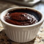 Close-up of rich, dark homemade chocolate pudding served in a white fluted ramekin.