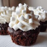 A rich, dark chocolate hot chocolate cupcake topped with white frosting and mini marshmallows.