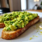 Close-up of bright green avocado toast topped with fresh parsley and lemon zest.