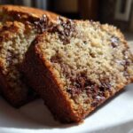 Two slices of moist banana bread recipe featuring melted chocolate chips, served on a white plate.