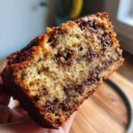 Close-up of a moist slice of chocolate chip banana bread recipe, showing rich chocolate swirls.