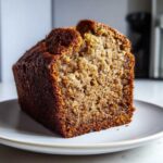 Close-up of a moist slice of hawaiian banana bread showing its rich brown crust and soft, textured interior.