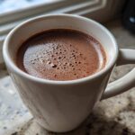 Close-up of a white mug filled with rich, frothy crockpot hot chocolate recipe.