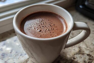 Close-up of a white mug filled with rich, frothy crockpot hot chocolate recipe.
