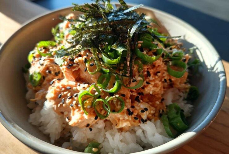 Close-up of a quick tuna rice bowl topped with spicy tuna mix, sesame seeds, green onions, and shredded nori.