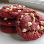 Close-up of a stack of vibrant red velvet cake mix cookies studded with white chocolate chips on a white plate.