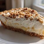 A generous slice of creamy millionaire pie featuring a graham cracker crust, thick filling, and crunchy nut topping.