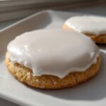 Close-up of a round sugar cookie topped with thick, smooth white sugar cookie icing recipe glaze.