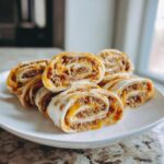 A stack of five savory taco pinwheels filled with seasoned ground beef and melted cheese, served on a white plate.