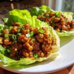 Two servings of savory chicken lettuce wraps filled with glazed ground chicken and topped with fresh green onions.