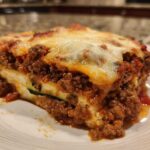 Close-up of a hearty slice of zucchini lasagna layered with rich meat sauce and melted cheese.