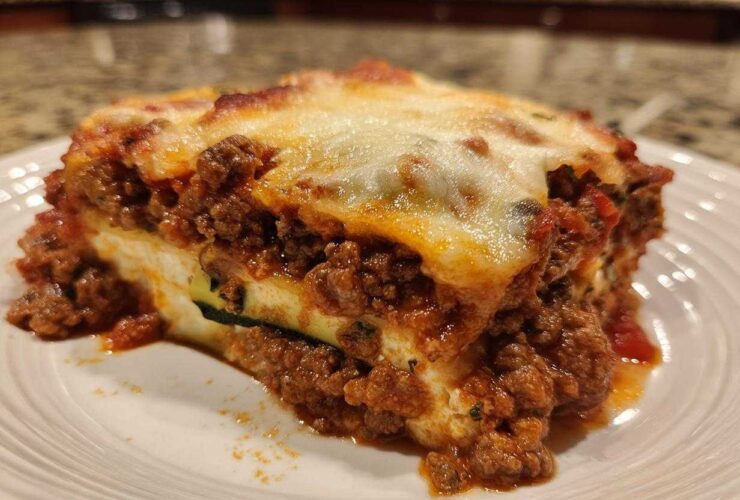 Close-up of a hearty slice of zucchini lasagna layered with rich meat sauce and melted cheese.