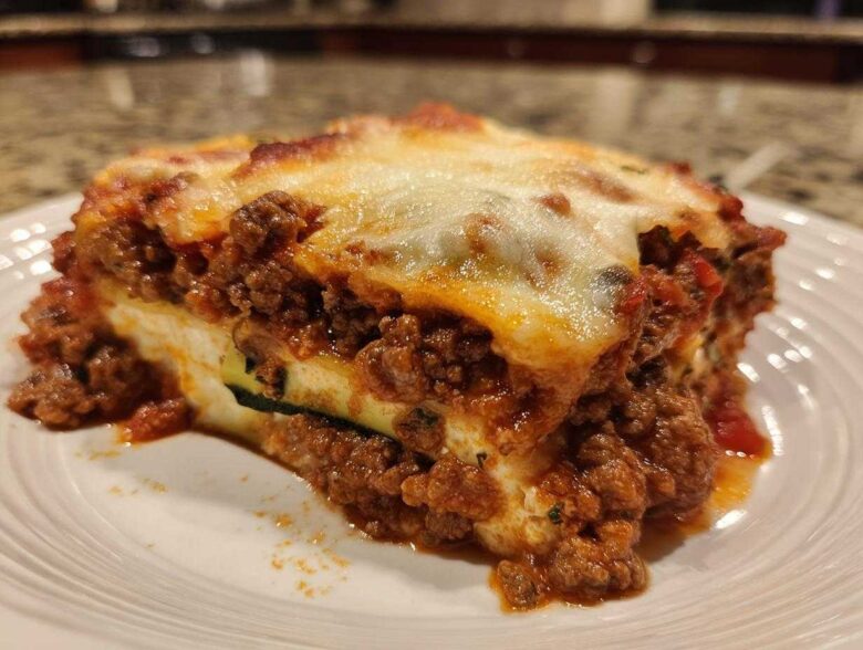 Close-up of a hearty slice of zucchini lasagna layered with rich meat sauce and melted cheese.