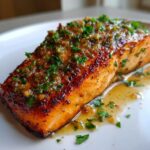 Close-up of a juicy, perfectly cooked air fryer salmon fillet topped with a savory garlic butter glaze and fresh parsley.