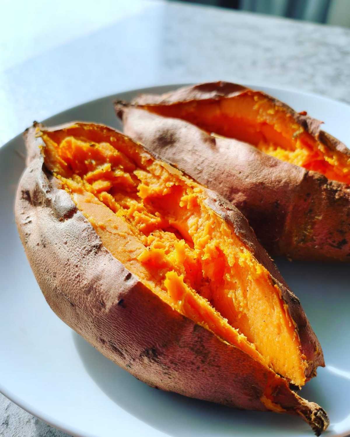Close-up of two halves of a perfectly baked sweet potato showing the bright orange, fluffy interior.