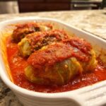 Three homemade cabbage rolls smothered in rich tomato sauce, ready to serve.