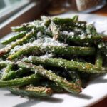 Close-up of roasted green beans topped with freshly grated Parmesan cheese, ready to serve.