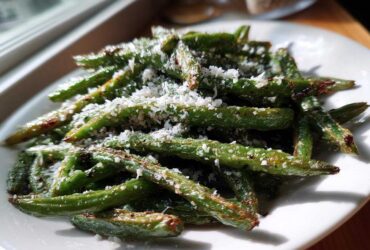 Close-up of roasted green beans topped with freshly grated Parmesan cheese, ready to serve.