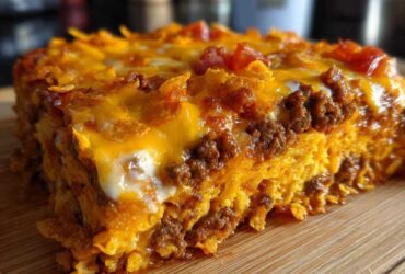 A thick, cheesy slice of Dorito Casserole showing layers of seasoned ground beef, melted cheddar, and crushed chips.