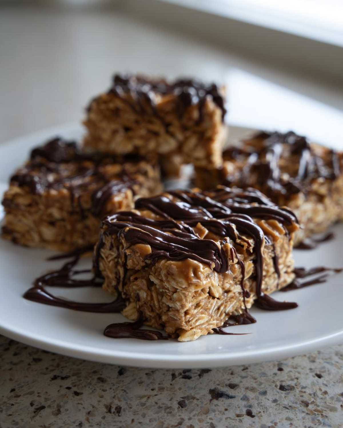 Four homemade protein bars made with oats and drizzled generously with melted dark chocolate.