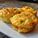 Three golden brown cottage cheese egg cups starbucks style served on a white rectangular plate.