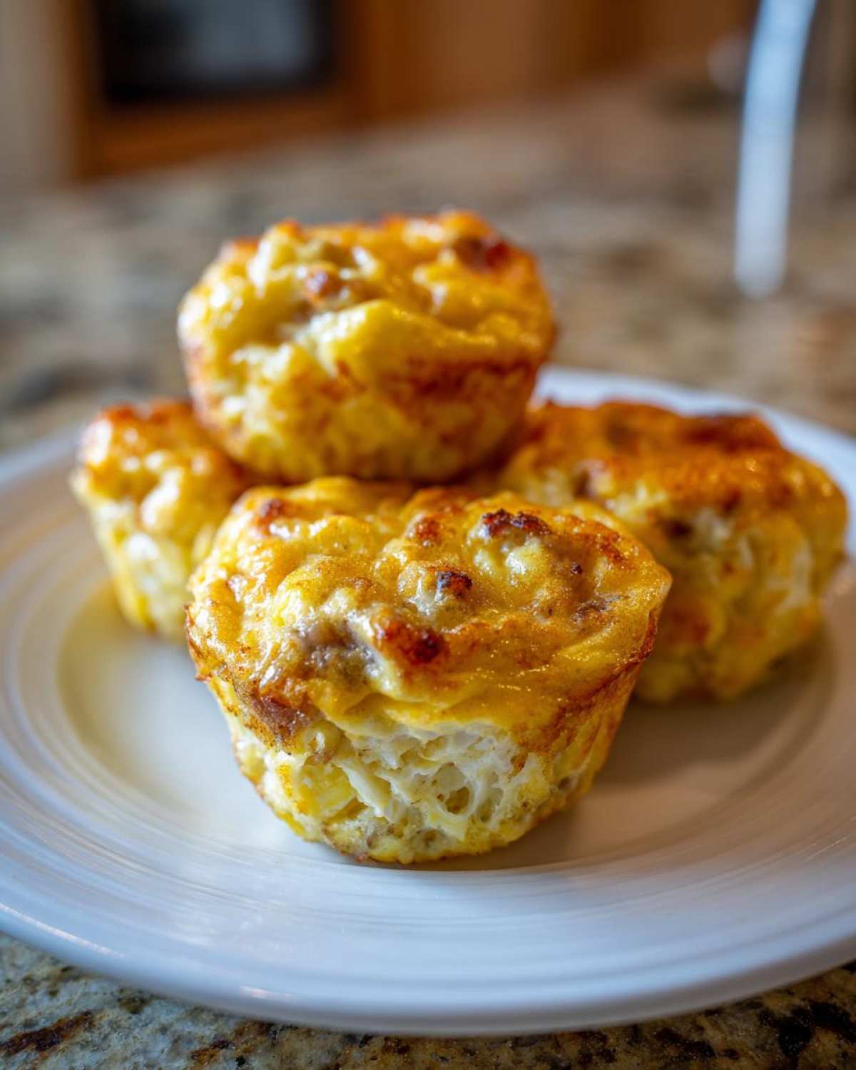 Four golden brown cottage cheese egg cups starbucks style stacked on a white plate.