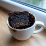A rich, dark chocolate Cottage Cheese Microwave Brownie baked inside a white mug.