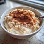 Close-up of a bowl of creamy rice pudding generously dusted with ground cinnamon.