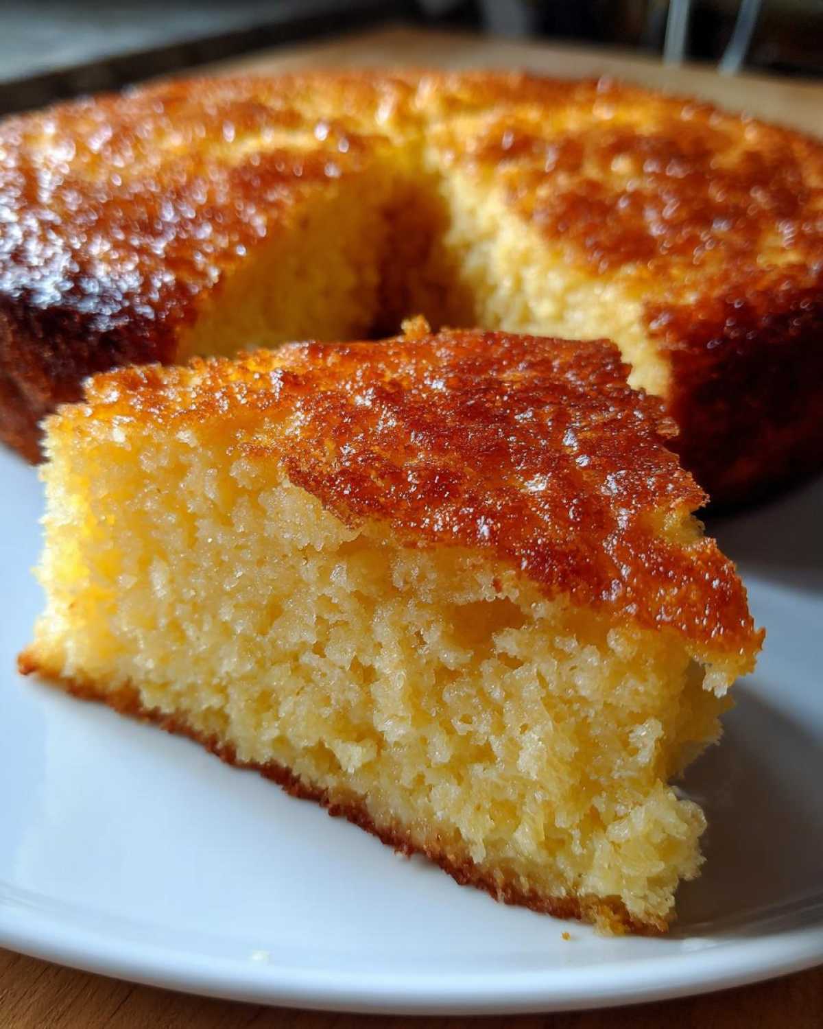 A close-up of a thick, golden slice of skillet cornbread with a crispy, shiny top crust.