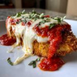 Close-up of a breaded chicken breast topped with marinara sauce, melted mozzarella, and fresh basil, representing Easy Chicken Parmesan.