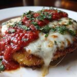 Close-up of a breaded chicken cutlet topped with melted mozzarella, marinara sauce, and fresh basil for Easy Chicken Parmesan.
